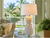 Large white pineapple ceramic table lamp displayed in an elegant tropical veranda with palm trees and natural furnishings