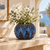 Handmade Thai ocean blue sea urchin ceramic vase with white flowers on a warm interior console