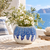 Ocean blue and white sea urchin ceramic vase with white flowers and greenery in a Mediterranean coastal setting