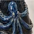 Close-up of sculpted octopus detailing and glossy blue reactive glaze on handmade ceramic vase