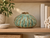 Green Moss ceramic vase styled on a wood shelf with neutral books and coastal decorative accents