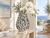 Handmade blue and white coral ceramic vase styled with greenery in a bright coastal interior