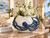 Ocean Embrace blue and white ceramic octopus bowl with white orchids, featuring hand-sculpted cobalt-blue tentacles in an elegant coastal interior.