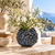 Blue barnacle ceramic vase with white flowers and greenery in a Mediterranean coastal setting