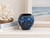 Ocean blue sand dollar ceramic vase displayed on a neutral coastal shelf with seaside decor