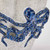 Close-up detail of the sculpted cobalt blue octopus and raised suction cups on the handmade ceramic vase.