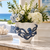 Small blue and white octopus ceramic vase styled with white and blue flowers in a bright coastal interior.