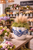 Small handmade blue and white octopus vase displayed with floral stems in a colorful boutique retail setting.