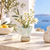 Light aqua blue and white scalloped ceramic vase styled with delicate flowers in an upscale coastal setting