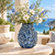Deep blue floral relief ceramic vase styled with delicate flowers in a bright seaside setting