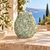 Green floral relief ceramic vase displayed without flowers on an elegant Mediterranean veranda
