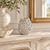 Handcrafted cream floral relief ceramic vase displayed without flowers on an elegant fireplace mantel