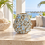 Handcrafted earth tone and blue floral ceramic vase displayed without flowers on a bright coastal lanai