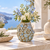 Earth tone and blue Bouquet De Fleurs ceramic vase styled with delicate flowers in an elegant coastal setting