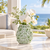 Green Bouquet De Fleurs ceramic vase styled with delicate white orchids and flowers in an elegant coastal setting
