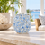 Handmade light blue floral relief ceramic vase displayed without flowers on a bright coastal lanai