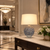 Flor Azul blue floral ceramic table lamp displayed on a console in an elegant hotel lobby with warm ambient lighting.