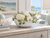 White ceramic bowl with green lily flowers filled with hydrangeas and orchids on a coastal bedroom dresser