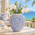 Large light blue floral ceramic vase styled with white orchids in an elegant tropical coastal setting