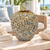 Medium celadon green floral relief ceramic vase displayed without flowers in a bright coastal interior