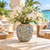 Small moss green ceramic floral vase styled with orchids and delicate flowers in a tropical lifestyle setting