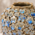 Close-up of sculpted floral relief and moss green glaze with blue accents on handmade Thai ceramic vase