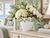 Handmade white and green ceramic lily vase with flowers styled on coastal bedroom dresser
