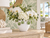 Small handmade white vase with green lily flowers styled with white hydrangeas and orchids in a coastal interior