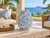 Light blue sculpted floral ceramic vase displayed without flowers in a tropical coastal lanai setting