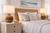 Brown abaca rope table lamp L150B styled on a bedside table in a bright coastal bedroom with soft neutral bedding.