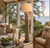 Round Teak Patch floor lamp beside seating in a sunlit tropical living room with large windows and lush greenery.