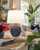 Handmade Thai blue oyster ceramic table lamp styled with books and tropical greenery