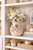 Small handmade cream octopus vase displayed with delicate flowers in a refined coastal room.