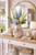 Small handmade cream octopus ceramic vase displayed with greenery on a console in an upscale coastal setting.