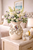 Small cream octopus ceramic vase styled with soft blue and white flowers in a bright coastal interior.