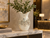 Extra large cream octopus ceramic vase styled with tall greenery on a marble table in a luxury hotel lobby.