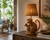 Handwoven wicker monkey table lamp L149M styled in a coastal living room with warm light filtering through the woven wicker shade.
