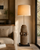 Antique teak wheelbase floor lamp illuminated beside a cream upholstered sofa in a neutral living room.