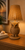 Handwoven wicker owl table lamp illuminated in a warm interior with the detailed owl figure and woven shade clearly visible.