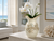 Large cream octopus ceramic vase styled with white orchids in a bright coastal living room.