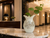 Large cream octopus ceramic vase displayed with greenery on a marble table in a luxury hotel lobby.