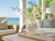 Large cream octopus ceramic vase styled with delicate flowering stems in a sunlit coastal lanai with ocean view.