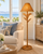 Natural wicker palm floor lamp in a sunlit coastal living room with soft neutral seating
