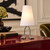 White Adam table lamp on a burgundy desk in an elegant eclectic study with an olive chair, classic wall molding, and abstract artwork.