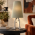 Sage Adam table lamp with sculptural silver feet on a dark side table beside a rust velvet chair in a classy eclectic living room.