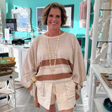 the striped pullover poncho is shown with the studded skort, pearl statement gold cuff bracelet and long matte gold disc and pearl necklace.