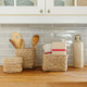 Sustainable and handwoven natural small square jute baskets perfect to help you and all your organization. Impeccable and meticulous detail in every basket. Perfect for storing utensils, spices, produce, and more. Stylish and durable storage solution from Will & Atlas. Displaying small square jute baskets with kitchen utensils on kitchen counter. 