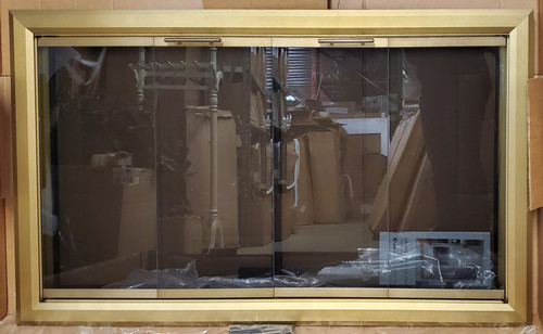 Clearance Custom Glass Fireplace Door (CL142) highlighting a wide, premium Bifold Legacy Lancaster frame in an elegant Vintage Brass finish with built-in cabinet mesh.