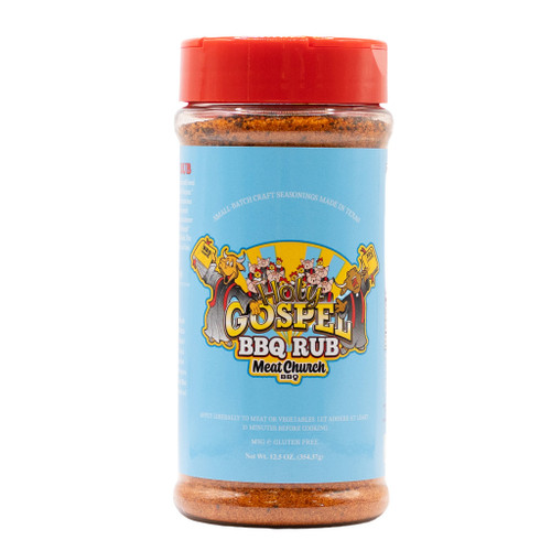 A close-up of a Meat Church "The Holy Gospel BBQ Rub" shaker bottle against a clean white background. The bottle features a vibrant light blue label with cartoon illustrations of a cow, pig, and chicken in a church-choir style setting, topped with a red lid.