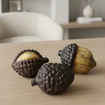 Three rustic decorative resin acorns with textured brown caps and warm golden wood-look finishes displayed on a tabletop, ideal for autumn and woodland-inspired home décor.